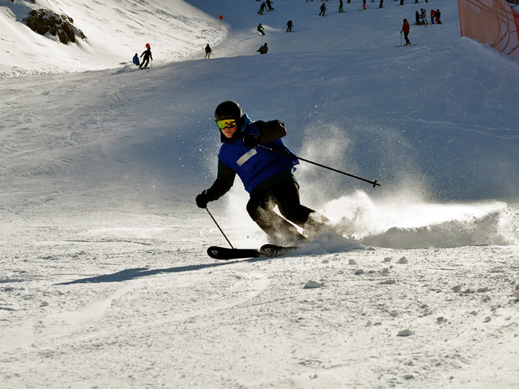 Skifahrer wirbelt beim Schwung den Schnee auf.